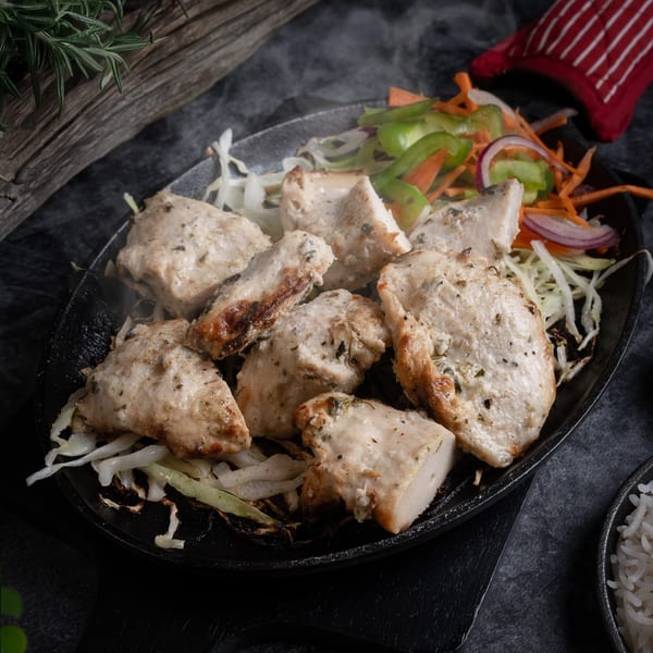 Steaming hot Indian chicken tikka with vegetables on a sizzling platter, served at Red Chillez Indian Cuisine.