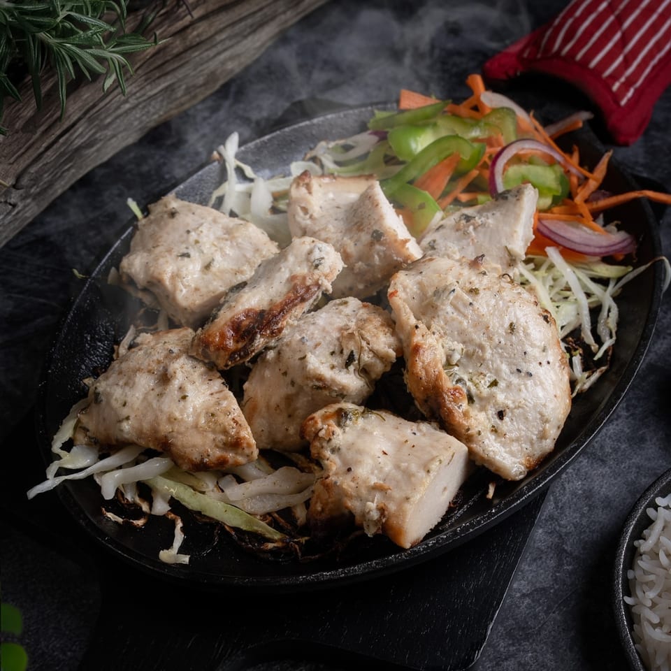 Steaming hot Indian chicken tikka with vegetables on a sizzling platter, served at Red Chillez Indian Cuisine.