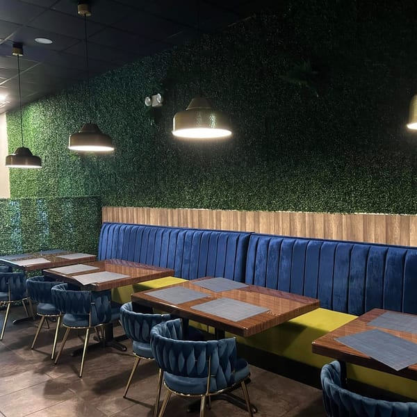 Interior of Red Chillez Indian Cuisine with blue velvet booths, wooden tables, and a green wall.