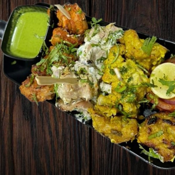 A platter of various Indian chicken dishes, including tandoori, malai, and hariyali, with green chutney.