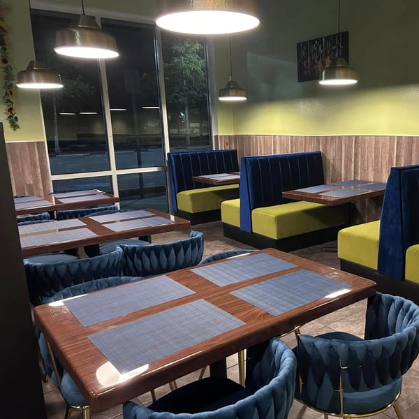Interior of Red Chillez Indian Cuisine with blue and lime green seating, wooden tables, and pendant lights.